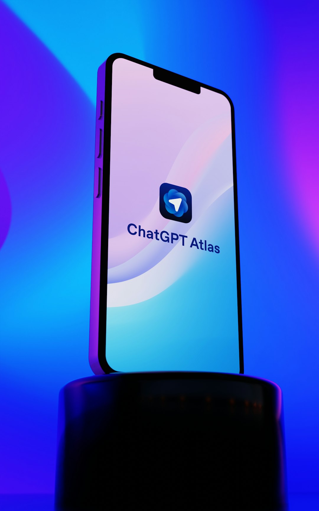 ChatGPT Atlas app displayed on a modern smartphone with sleek gradient background blending vibrant purple, blue, and cyan colors. The minimalist interface showcases the distinctive blue messenger-style icon and app branding on a device with dynamic island design. Perfect representation of cutting-edge AI technology, mobile applications, and contemporary digital innovation in artificial intelligence communication tools.