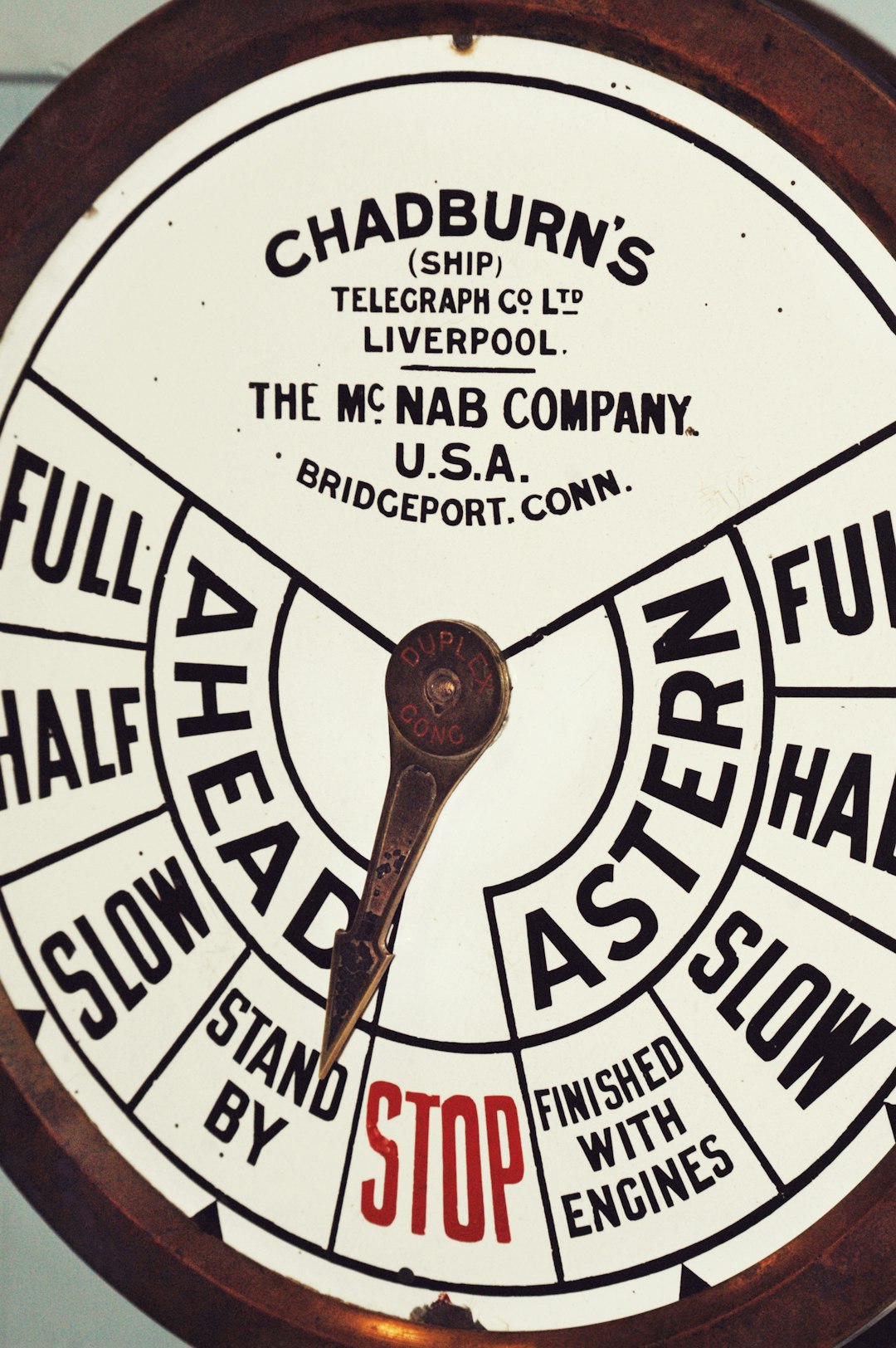 Detail shot of a ship or vessels propulsion system, filled with large text print and words giving speed readouts. Patina covers the metal round dial and needle.